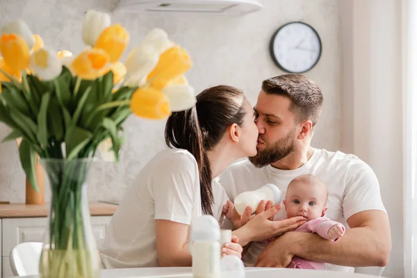 O familie fericită hrănind bebelușul în bucătărie . — Fotografie, imagine de stoc