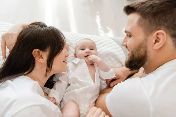 O familie tânără zâmbitoare fericită în pat cu bebelușul — Fotografie, imagine de stoc