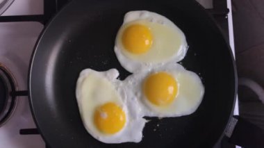 Üç tavuk yumurtası demir tavada kızartılıyor.