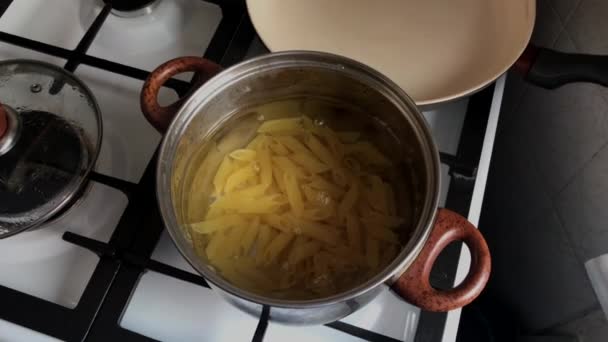 Vrouwelijke hand stoppen met pasta in kokend water. — Stockvideo