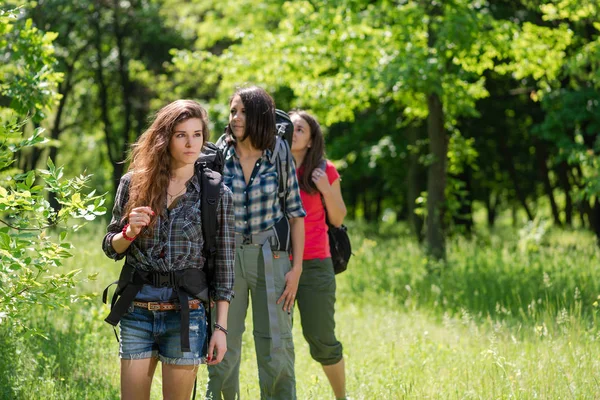 Tre kvinnliga turister i skogen med ryggsäckar — Stockfoto