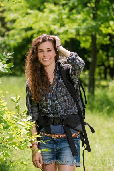 Happy girl tourist with backpack in forest — Stock Photo, Image