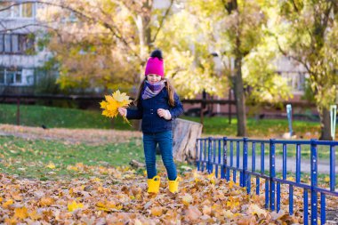 bir kucak dolusu sarı yaprakları ile kız.