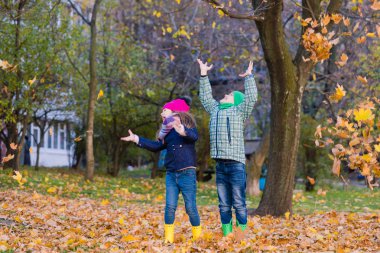 İki çocuk parkta akçaağaç yaprakları ile oynamak