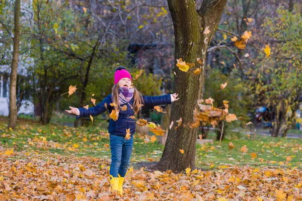 Lycklig flicka kasta lönnlöv i parken — Stockfoto