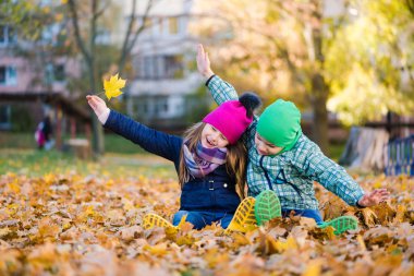 Sevimli çocuklar kucaklar ve sonbahar yaprakları oturup