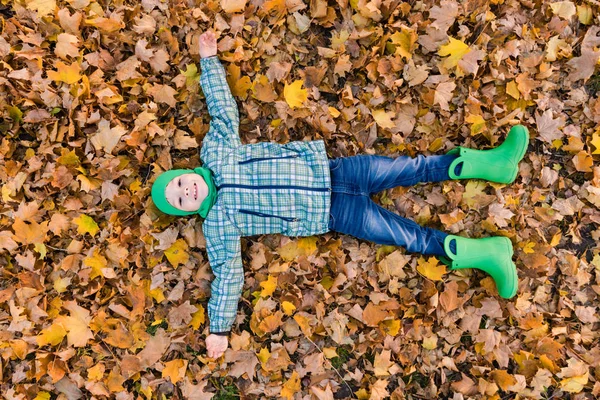 Happy preeten pojke låg på Maple lövverk — Stockfoto