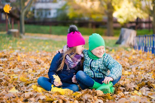 Preteen pojke och flicka leka med gult lövverk — Stockfoto