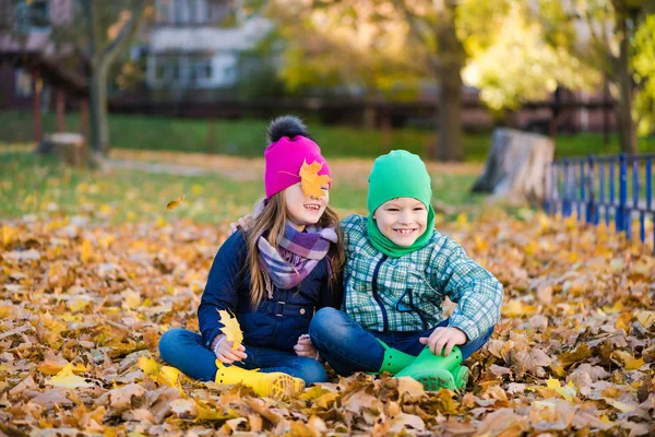 Söta barn leka med lönnlöv utanför — Stockfoto