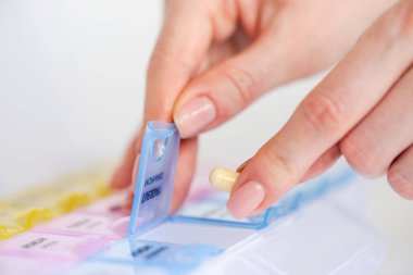 Woman's hand opening a pill organizer box clipart