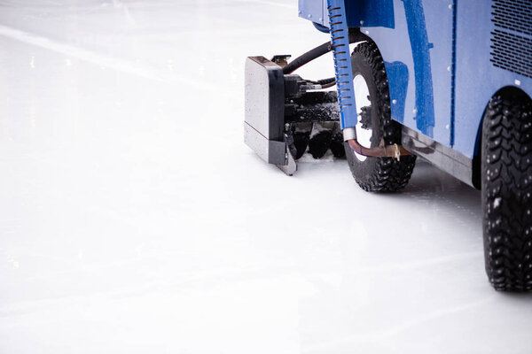 Resurfacing machine cleaning ice of hockey rink.