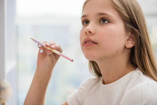 Inspirado menina da escola olhar para cima lápis na mão direita — Fotografia de Stock
