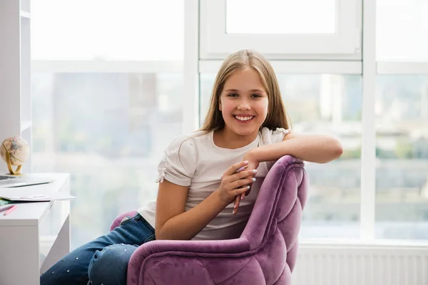 Sonriendo preeten estudiante chica se sienta en una silla . — Foto de Stock