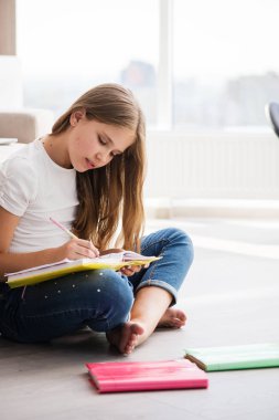 Deftere resim yazan veya çizen kız yere otur