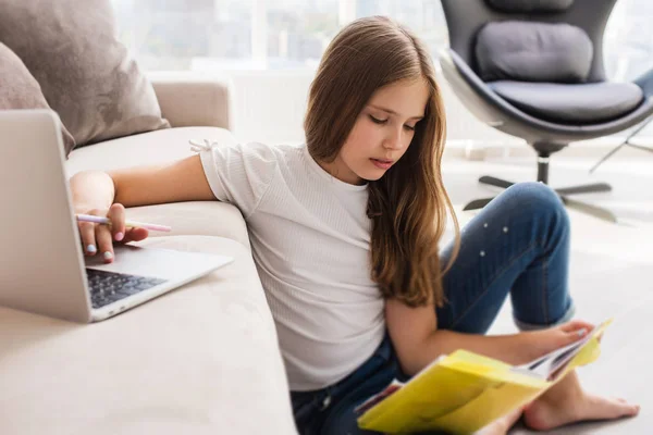 自宅でノートパソコンと本で学ぶ女子高生 — ストック写真