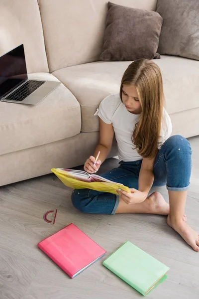 Escuela chica estudio con portátil y libro en casa — Foto de Stock