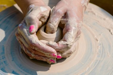 Kadın eller çömlekçi tekerlek üzerinde kil yemekleri yapmak.