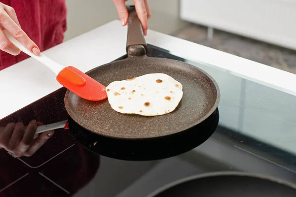 Kadın kuru tavada tortilla pişiriyor.