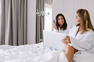 Laptop ve kredi kartı olan iki kadın.