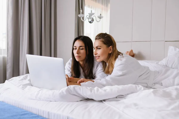 Twee geconcentreerde vrouwen in bed met laptop — Stockfoto