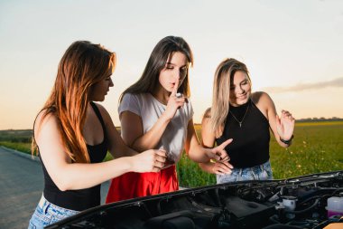 Şehir dışına giderken üç kız arkadaş sorun yaşadı. Ayrıntıları kontrol etmek ve sakinleşmek için kaputu açtılar.