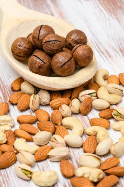 Tahta bir arka planda tahta kaşıkta Macadamia fındıklarının yakın çekimi. Tahta bir masada çeşitli fındık çeşitleri..