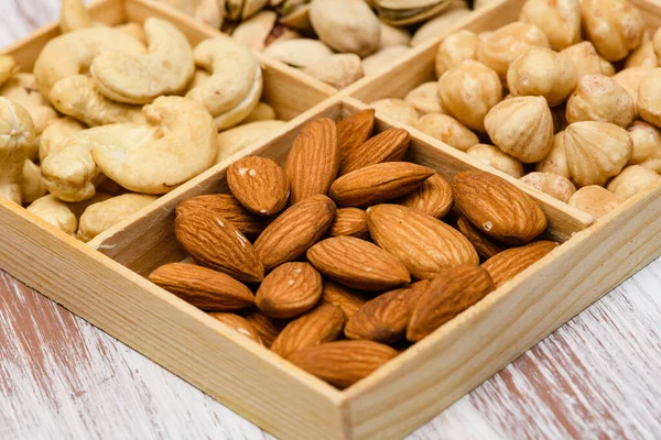 Close-up of almonds in a wooden box. Assortment of nuts in the background.