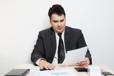Takım elbiseli gülümseyen iş adamı belge masada bakar defter, kağıt, kalem