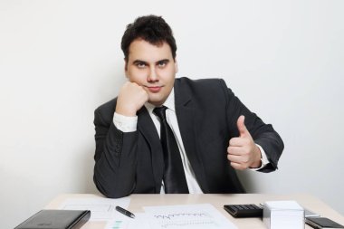 İşadamı takım elbise başparmak yukarıya tablo defter, kağıt, kalem, hesap makinesi ile gülümseyen