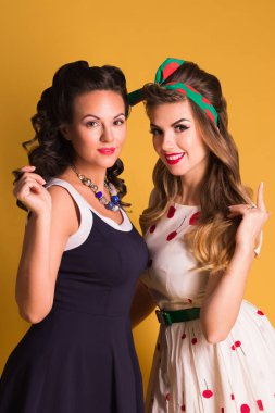 İki gülümseyen kadın elbise poz turuncu Studio, toplu iğne stili