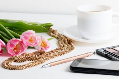 Pembe laleler, mücevherat, kozmetik, kalem, kahve olan kadın şeyler beyaz masaya - bahar