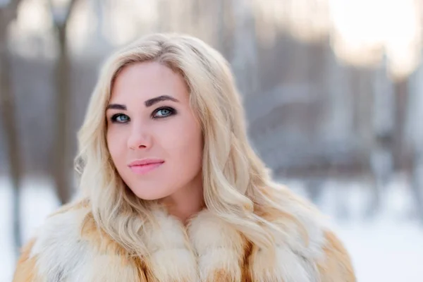 穿着毛皮大衣的漂亮年轻的金发女郎在冬天的户外微笑 — 图库照片