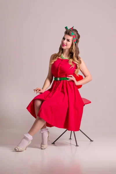 Happy Girl Red Dress Hairdo Sits Chair Grey Studio Pin — Stock Photo, Image