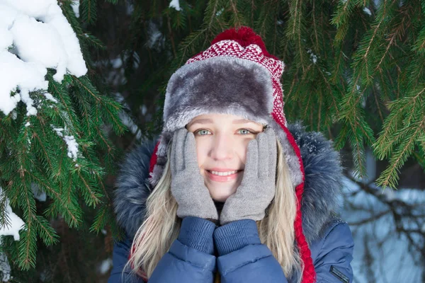 Genç ve güzel kadın şapkalı yanakları yeşil çam ağacı Kışın açık yakınındaki dokunur