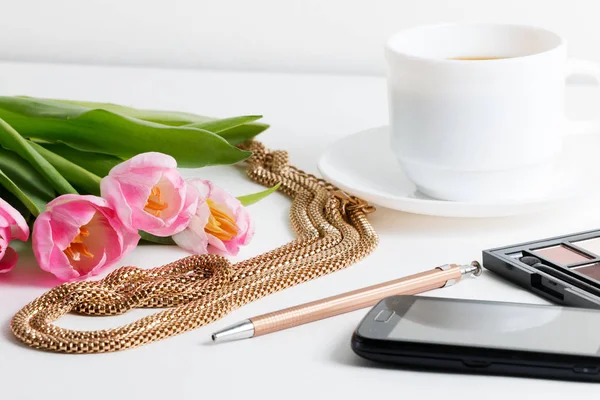 Pembe laleler, mücevherat, kozmetik, kalem, kahve olan kadın şeyler beyaz masaya - bahar