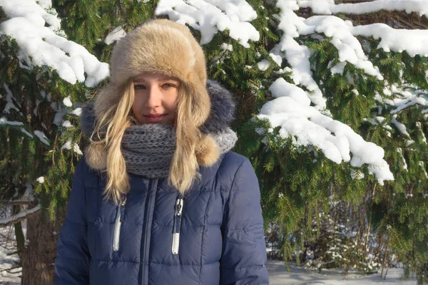 Kürk şapka standları yakınındaki yeşil çam ağacı güneşli kış günü açık genç ve güzel kadın