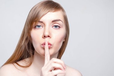 Güzel genç kadın portre kadar yakın makyaj sessiz jest studio, gösterir.