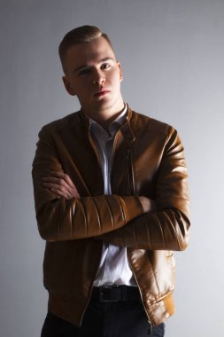 Deri ceketli yakışıklı genç adam uzakta gri studio görünüyor