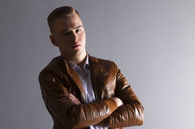 Deri ceketli yakışıklı adamı gri Studio çapraz silah ile poz veriyor