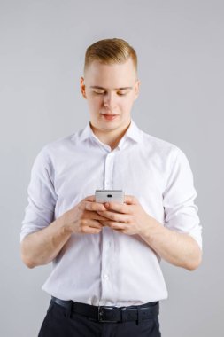 Studio smartphone ile mutlu delikanlı beyaz gömlekli duruyor