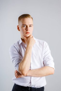 Genç yakışıklı beyaz adam beyaz gömlekli Studio çenesine dokunuyor