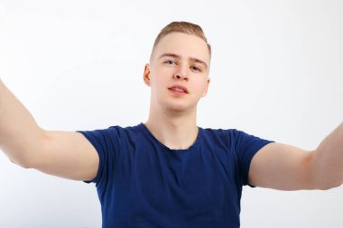 Genç sarışın yakışıklı adam mavi gömlekli selfie beyaz studio yapar.