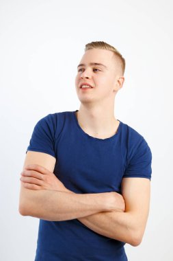 Mutlu yakışıklı delikanlı mavi tişört ve kot pantolon beyaz Studio çapraz silah ile poz veriyor