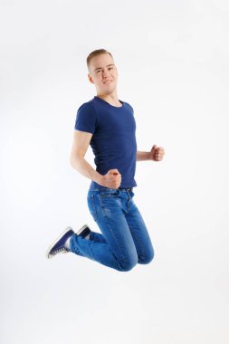 Mutlu yakışıklı delikanlı mavi tişört ve kot pantolon beyaz studio, tam vücut atlar