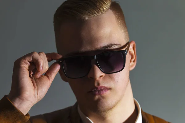 Schöner Mann Lederjacke Berührt Seine Sonnenbrille Grauen Studio Nahaufnahme — Stockfoto