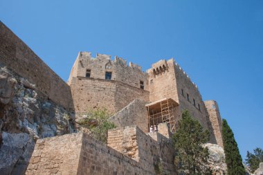 Lindos Acropolis, Rodos, Yunanistan, mavi gökyüzü, zeytin ağacı ve güzel deniz manzaralı arka planda Hellenistik stoa sütunlarda