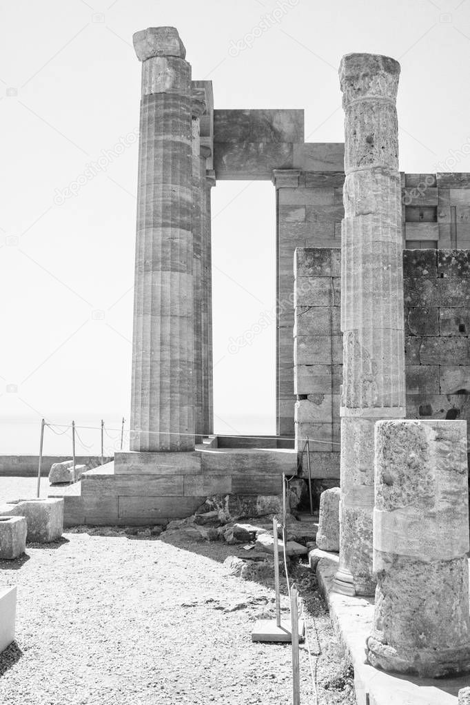 Columns on the hellenistic stoa of the Acropolis of Lindos, Rhodes, Greece, Blue sky, olive tree and beatiful sea view in the background