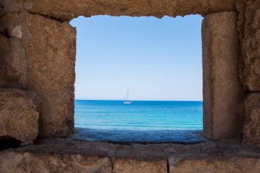 The yacht on the background of the mills in the Mediterranean harbor Mandraki. Rhodes Island. Greece