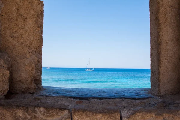 The yacht on the background of the mills in the Mediterranean harbor Mandraki. Rhodes Island. Greece