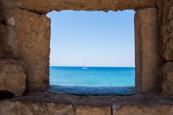 The yacht on the background of the mills in the Mediterranean harbor Mandraki. Rhodes Island. Greece